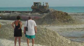 beach walkers watch beach restoration in progress